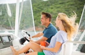Couple enjoying the wind in their hair while cruising on a power catamaran