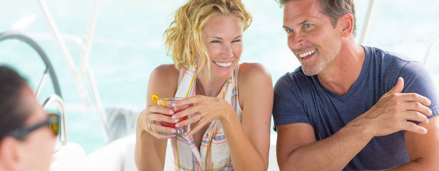 Happy couple drinking cocktails on a luxury crewed yacht